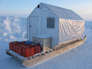 Traveling shelter built on Komatik sled with gas jugs tied on the back.