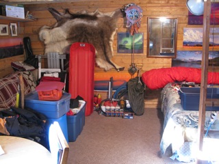 Sorting expedition gear inside our log cabin, with a caribou skin tacked on the far wall.